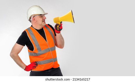 Builder shouts into megaphone. Man builder is holding megaphone. Worker in builder's uniform. Blank for your building advertising. Copy space on gray. Message from construction company concept - Powered by Shutterstock