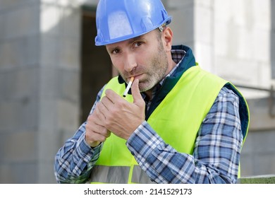 builder smoking cigarette on construction site - Shutterstock ID 2141529173