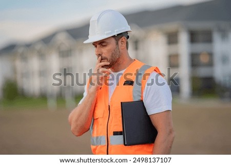 Builder thinking. Serious engineer at new home. Construction manager in helmet. Architect at a construction site. Handyman builder in hardhat. Building concept. Builder foreman.