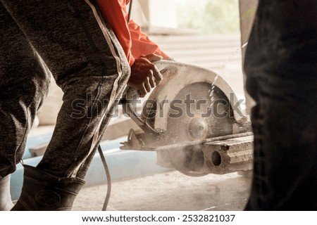 A builder using a circular saw to cut a large concrete piece