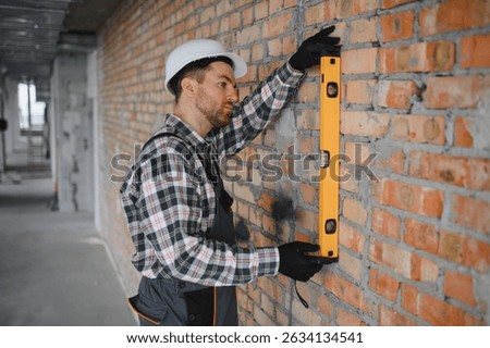 Builder using a spirit level ensures the perfect vertical alignment of a brick wall during a construction or renovation project
