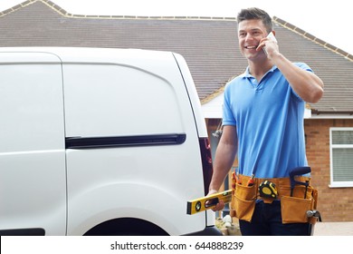 Builder With Van Talking On Mobile Phone Outside House