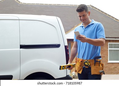 Builder With Van Texting On Mobile Phone Outside House