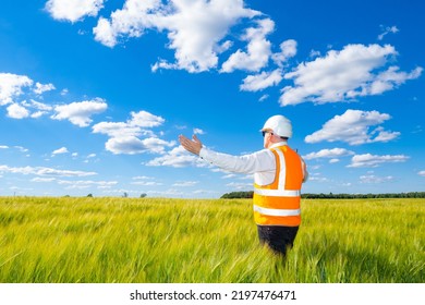 Builder Is Walking Across Field. Man In Builder Uniform. Construction Planning For On Territory Field Concept. Construction Company Worker Back To Camera. Selection Picturesque Area For Construction