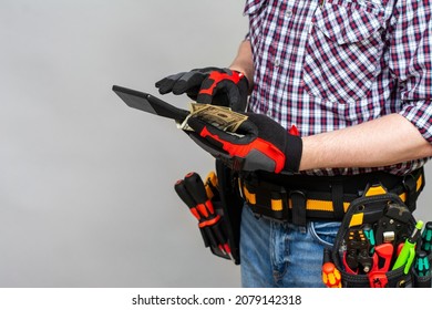 Builder worker with a bag of tools on his belt holds a calculator in his hands. The concept of concluding a contract and drawing up an estimate for the performance of installation work. Copyspace