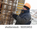 Builder worker making reinforcement metal framework lattice for concrete pouring