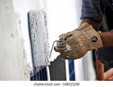 builder worker painting facade of high-rise building with roller 