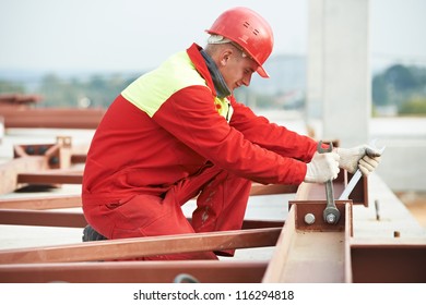 Builder Worker In Safety Protective Equipment Assembling Metal Construction Frame With Electric Spanner Tool