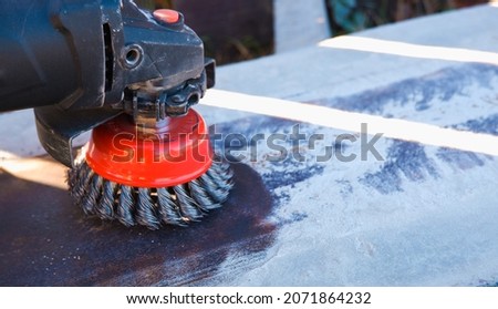 The builder works with an angle grinder. Wire cleaning brush. Cleaning metal embedded from rust and concrete. Worker using grinder to clean rust from metal