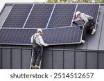 Builders building photovoltaic solar module station on roof of house. Men electricians in helmets installing solar panel system outdoors. Concept of alternative and renewable energy.