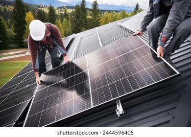 Builders building photovoltaic solar module station on roof of house. Men electricians in helmets installing solar panel system outdoors. Concept of alternative and renewable energy. - Powered by Shutterstock