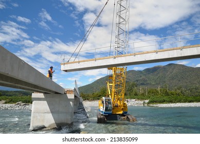 Builders Construct A Concrete Bridge Over A Small River In Westland, New Zealand