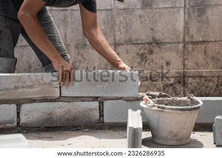 Builders skillfully lay blocks, crafting sturdy walls for a remarkable house. Creating a strong foundation for the dream home. Creating sturdy base for dream home with precision and craftsmanship.