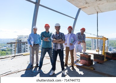 Builders Team Leader With Group Of Apprentices At Construction Site Over City View Background, Happy Smiling Engineers