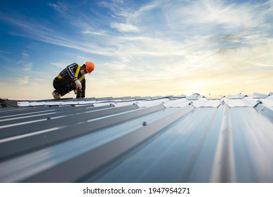 Builders in work clothes install new roofing tools, roofing tools, electric drill and use them on new wooden roofs with metal sheets
