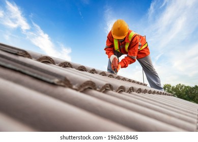 Builders in work clothes install new roofing tools, roofing tools, electric drill and use them on new wooden roofs with metal sheets