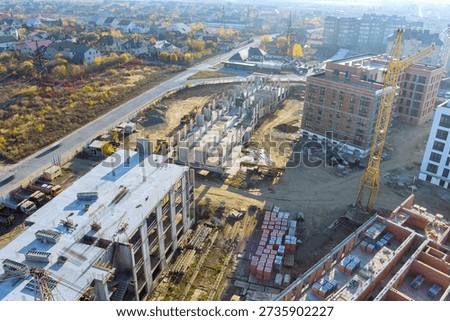 Builders work on constructing new buildings at construction site with using cranes in city