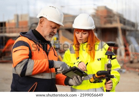 Builders Workers collaborating on a construction site while checking plans on a tablet
