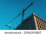 building around crane construction equipment. Construction of apartment building from concrete, monolithic slabs. Industrial construction of houses,developer company,construction crane.