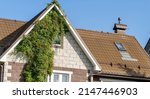Building attic house construction with different types of roof designs. Beige metal roof tile and smokestack. Modern chimney on beige roof with snow retainers.