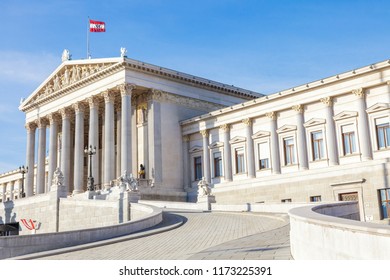 The Building Of The Austrian Parliament With A Fluttering National Flag On The Blue Sky. Vienna