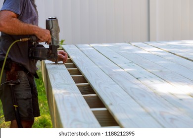 Building a backyard deck with worker putting with nail gun patio construction terrace