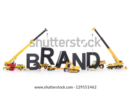 Building up a brand concept: Black alphabetic letters forming the word brand being set up by group of construction machines, isolated on white background.