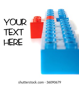 Building bricks in blue and one red block being unique and standing out. Over white background with shadows to show depth. Focus is on the block standing out.