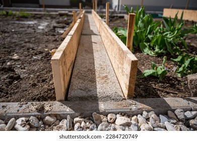 Building a concrete path through vegetable garden using wooden planks. - Shutterstock ID 2284720749