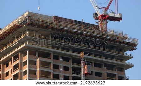 Building constriction site with scaffolding and crane. Red crane machine in action. Blue sky background. Foto d'archivio © 