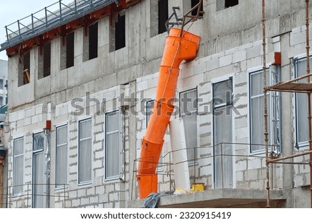 Building construction and debris chute on facade of new building, disposal of construction waste during construction work. Removing debris and waste, dispose of garbage from different levels