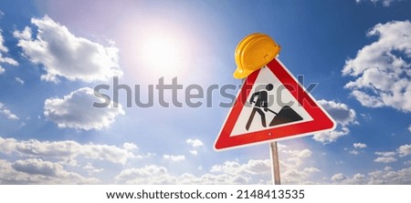 building construction site Street DANGER Sign, with yellow helmet against blue cloudy sky. Under construction concept image