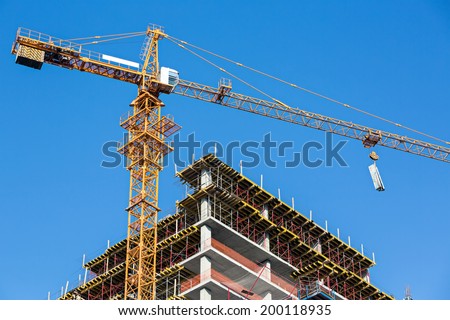 Building construction site with tower crane against blue sky