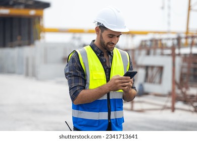 building and construction worker using mobile phone, Hiapanic latin male wearing safety hard hat helmet standing with arms crossed at construction site and looking at camera - Powered by Shutterstock