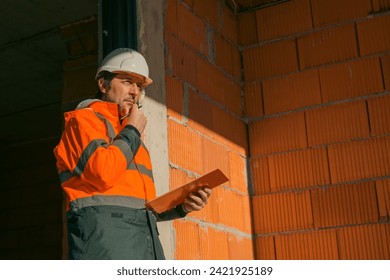 Building contractor and construction engineer making sketches and writing notes on building site, selective focus