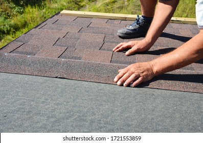 A building contractor is installing  dimensional asphalt roof shingles on the underlayment of the house construction repairing the rooftop. - Shutterstock ID 1721553859
