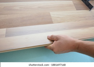 A building contractor is installing wood laminate flooring on underlayment. - Shutterstock ID 1881697168