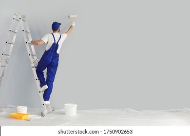Building contractor painting grey wall with roller brush, copy space text. Construction worker renovating house - Shutterstock ID 1750902653