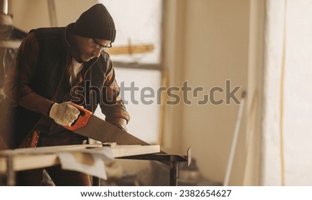 Building contractor renovating a kitchen, using a saw to cut wood. He is focused on the home improvement project, undertaking remodeling and refurbishment work with precision.