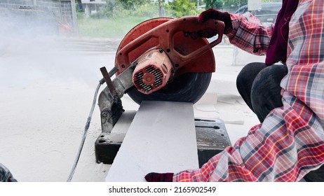 Building Contractor Using An Angle Grinder Outdoors To Cut Through A Paving Slab Or Brick In A Cloud Of Dust.