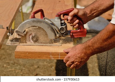 Building Contractor Worker Using Hand Held Worm Drive Circular Saw To Cut Boards On A New Home Construction Project