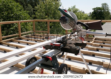 Building contractor worker using hand held worm drive circular saw to cut boards on a new home constructiion project