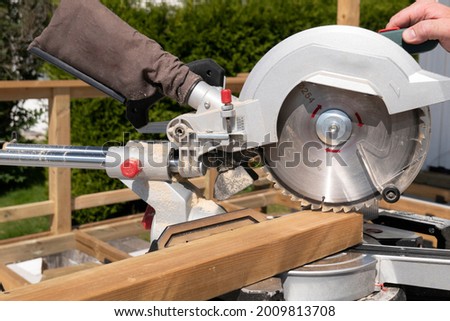 Building contractor worker using hand held worm drive circular saw to cut boards on a new home constructiion project