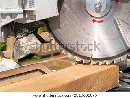 Building contractor worker using hand held worm drive circular saw to cut boards on a new home constructiion project