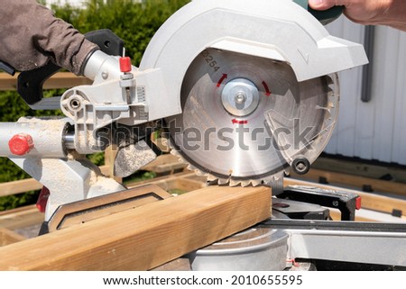 Building contractor worker using hand held worm drive circular saw to cut boards on a new home constructiion project