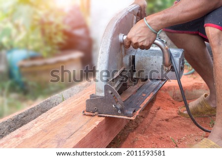 Building contractor worker using hand held worm drive circular saw to cut boards on a new home constructiion project. a circular saw in the cutting a wooden plank