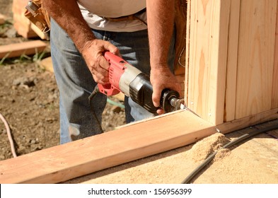 Building contractor worker using a reciprocating saw to cut out the door in the base plate of the wall for the first floor on a new home construction project - Shutterstock ID 156956399