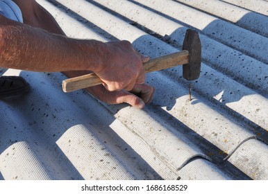 A Building Contructor Is Nailing The Asbestos Roof Tile With A Hammer.