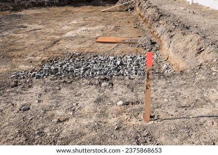 Building corner survey marker, base dug out of leveled dirt and ready for foundation installation of a new home
