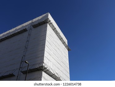 Building Covered In White Blank Wrap New Under Construction With Bright Blue Clear Sky